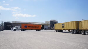 Unidades con contenedores frente a las instalaciones de un patio logístico